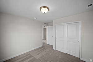 Unfurnished bedroom with light carpet and a closet