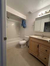 Full bathroom featuring vanity, shower / bathtub combination, toilet, and a textured ceiling