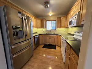 Kitchen with appliances with stainless steel finishes, light wood-type flooring, and sink