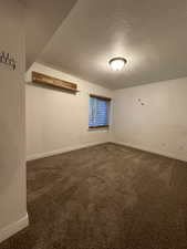 Empty room featuring dark carpet and a textured ceiling