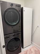 Washroom featuring stacked washer and dryer and light tile patterned floors