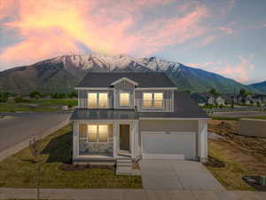 View of front of house with a mountain view, a porch, a garage, and a lawn