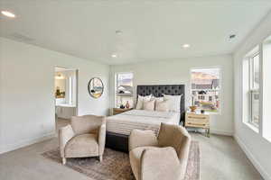 Bedroom featuring light colored carpet, a textured ceiling, and connected bathroom