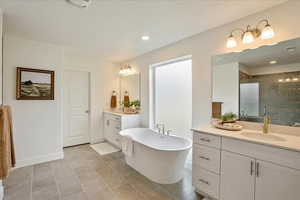 Bathroom featuring tile patterned floors, vanity, shower with separate bathtub, and a textured ceiling