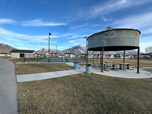 View of community featuring a lawn and tennis court