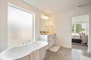 Bathroom featuring tile patterned floors, vanity, a tub, and a textured ceiling