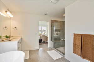 Bathroom featuring tile patterned floors, vanity, separate shower and tub, and a textured ceiling