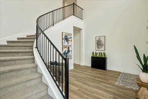 Stairway featuring hardwood / wood-style flooring and a towering ceiling