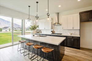 Kitchen featuring sink, wall chimney exhaust hood, gas cooktop, a mountain view, and decorative light fixtures