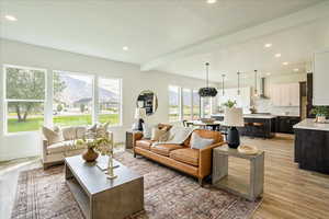 Living room with light hardwood / wood-style flooring and beamed ceiling