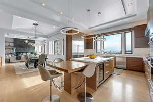 Kitchen featuring decorative light fixtures, a kitchen island, a wealth of natural light, and a tray ceiling