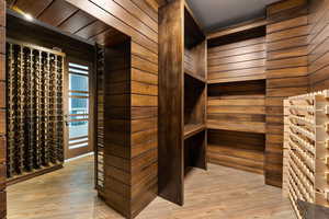 Wine room with wood walls and light hardwood / wood-style flooring