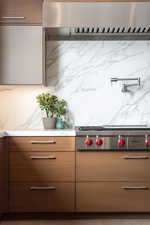 Kitchen with decorative backsplash, extractor fan, and stainless steel gas stovetop