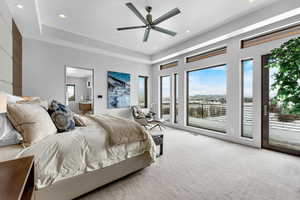 Bedroom featuring a tray ceiling, access to exterior, ceiling fan, and light colored carpet