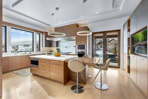 Kitchen with decorative backsplash, light wood-type flooring, hanging light fixtures, and an island with sink