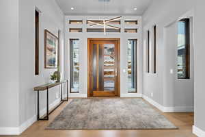 Foyer entrance with a wealth of natural light, light hardwood / wood-style floors, and an inviting chandelier