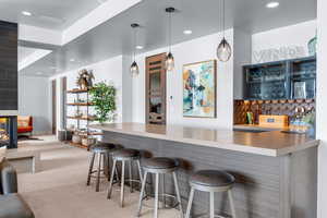 Bar with pendant lighting, sink, light carpet, and tasteful backsplash