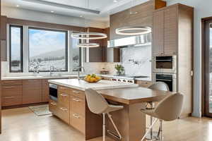 Kitchen featuring sink, hanging light fixtures, tasteful backsplash, a mountain view, and a kitchen island with sink