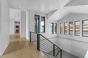 Hallway with light hardwood / wood-style floors and lofted ceiling