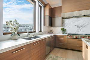 Kitchen with sink, stainless steel gas cooktop, light hardwood / wood-style flooring, backsplash, and exhaust hood