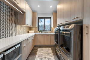 Laundry room featuring separate washer and dryer, sink, and cabinets