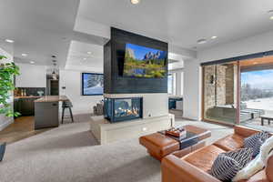 Living room with carpet flooring, a tiled fireplace, and a wealth of natural light