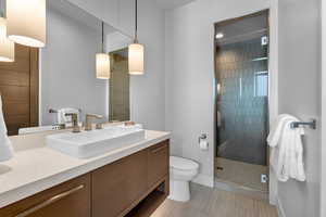 Bathroom with tile patterned floors, vanity, an enclosed shower, and toilet