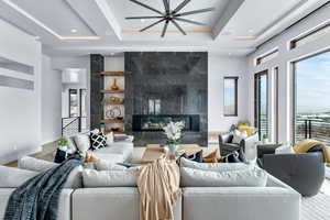 Living room featuring a tray ceiling, built in features, ceiling fan, and a premium fireplace