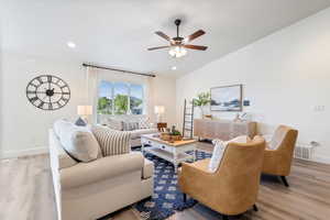 Living room featuring ceiling fan, light wood-type flooring, and vaulted ceiling