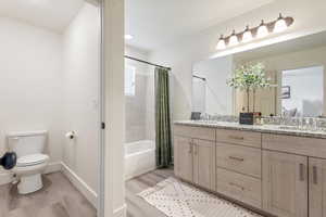 Full bathroom with hardwood / wood-style flooring, vanity, toilet, and shower / tub combo