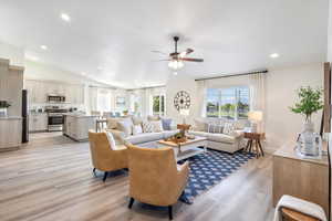 Living room featuring ceiling fan, light wood-type flooring, and lofted ceiling