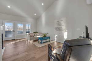 Living area with high vaulted ceiling, recessed lighting, baseboards, and light wood finished floors