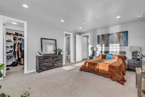 Bedroom with light carpet, ensuite bathroom, a spacious closet, and a closet