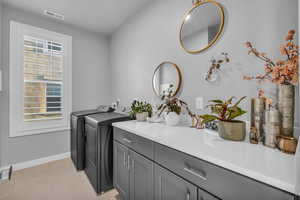 Laundry room with cabinets, light tile patterned floors, and washing machine and clothes dryer