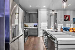 Kitchen featuring a center island with sink, hanging light fixtures, sink, appliances with stainless steel finishes, and tasteful backsplash