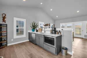 Kitchen with gray cabinetry, built in microwave, dishwasher, sink, and light hardwood / wood-style floors