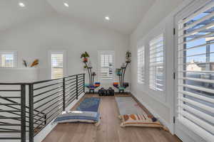 Exercise room featuring high vaulted ceiling, recessed lighting, wood-type flooring, and baseboards