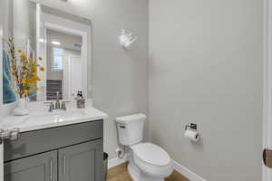 Half bathroom with toilet, baseboards, visible vents, and vanity