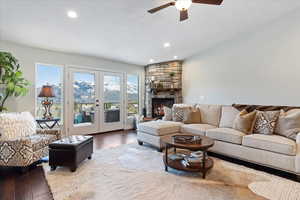 Living room with a fireplace, french doors, dark hardwood / wood-style floors, and ceiling fan