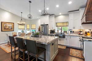 Kitchen featuring white cabinetry, sink, an island with sink, pendant lighting, and appliances with stainless steel finishes