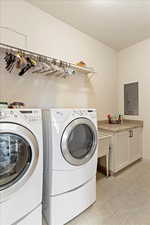 Laundry room featuring cabinets, independent washer and dryer, a textured ceiling, and electric panel