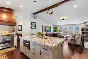 Kitchen with backsplash, custom exhaust hood, pendant lighting, range with two ovens, and a kitchen island