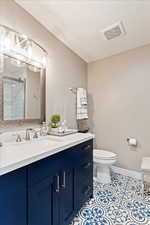 Bathroom with a shower with door, vanity, a textured ceiling, and toilet