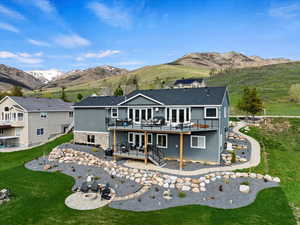 Back of property with a lawn, a deck with mountain view, and a fire pit