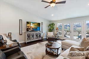 Living room with ceiling fan, dark hardwood / wood-style floors, lofted ceiling, and french doors