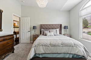 Carpeted bedroom featuring a chandelier and lofted ceiling