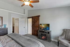 Carpeted bedroom with ceiling fan, a barn door, a textured ceiling, and vaulted ceiling