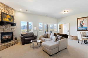 Living room with a stone fireplace, light carpet, and a textured ceiling