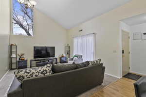 Living room featuring hardwood / wood-style flooring, vaulted ceiling, and a chandelier