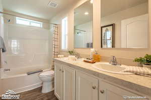 Full bathroom featuring vanity, hardwood / wood-style floors, shower / bathtub combination with curtain, and toilet